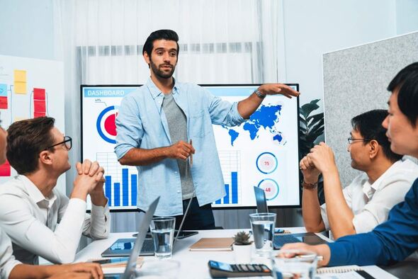 A man presenting to a group of colleagues in a conference room, engaging them with visual aids.